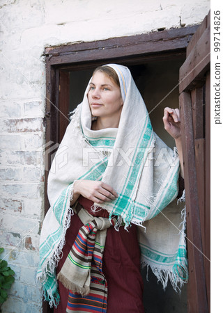 A woman in ancient clothes is standing at the door 99714826
