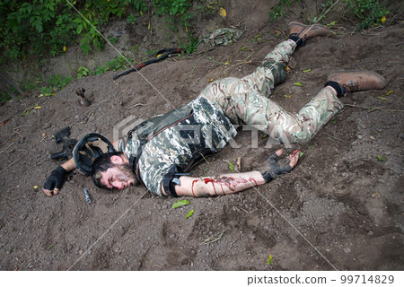A wounded soldier lies on the ground 99714829