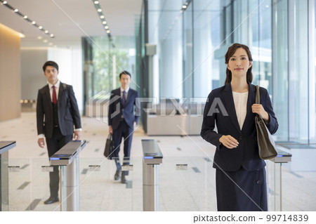 男性和女性商人通過安全門進入辦公樓 男性和女性商人通過安全門進入辦公樓 99714839