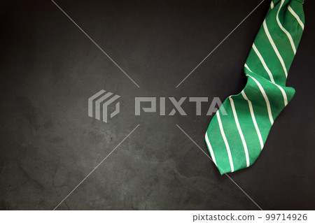 stylish tied green striped tie on dark concrete background top view, copy space, men,business,meeting,party concept 99714926