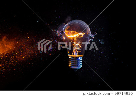 Struck electric bulb breaks into fragments, tungsten filament lit 99714930