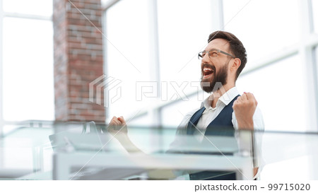 very happy businessman sitting at the office Desk 99715020