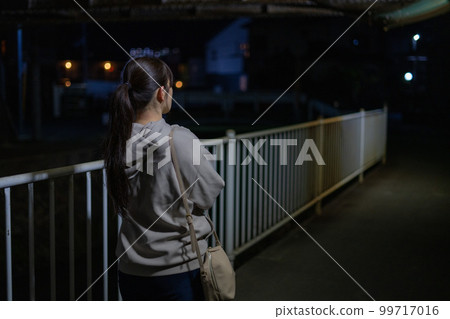 Back view of a woman walking on the night road Back view of a woman walking on the night road 99717016