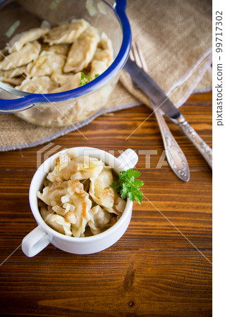 cooked dumplings with potatoes and fried onions on a wooden table. 99717302