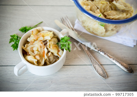cooked dumplings with potatoes and fried onions on a wooden table. cooked dumplings with potatoes and fried onions on a wooden table. 99717305