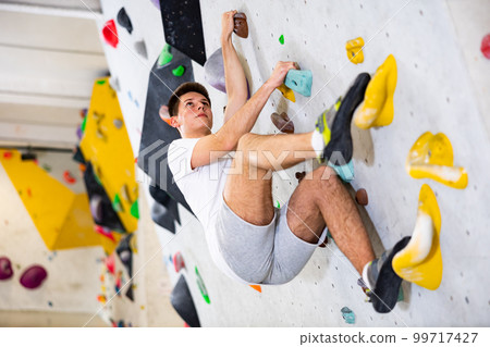 Man training at bouldering gym without special climbing equipment 99717427