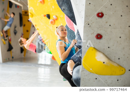 Bouldering, people and healthy lifestyle concept - young woman exercising at climbing gym Bouldering, people and healthy lifestyle concept - young woman exercising at climbing gym 99717464