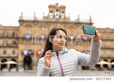 Woman is taking photos on her camera while journey through the Plaza Mayor. Spain 99717465