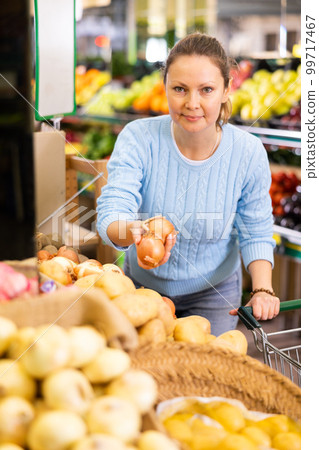 woman buy large onion in supermarket 99717467