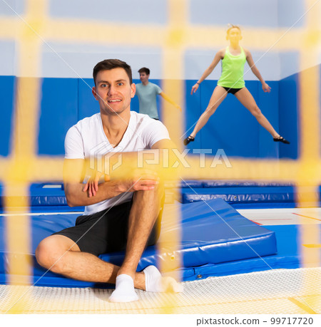 Happy man on break during workout on trampoline Happy man on break during workout on trampoline 99717720