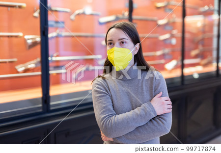 Woman in protective mask examining ancient guns in weapons museum 99717874