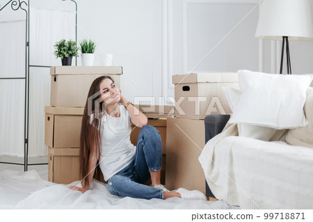 happy young woman sitting on the floor in her new apartment happy young woman sitting on the floor in her new apartment 99718871