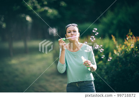 attractive young woman playing with soap bubbles in summer Park attractive young woman playing with soap bubbles in summer Park 99718872