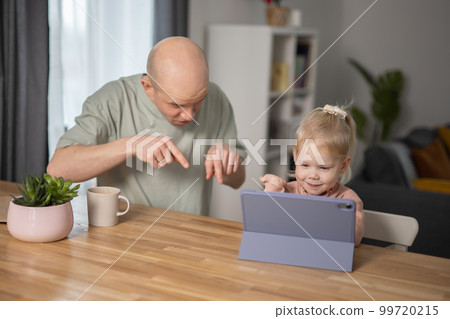 People with cochlear implant system. Kid study to hear with her father, learning with video on tablet. Installation cochlear implant on child girl ear for restores hearing. 99720215