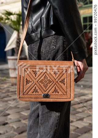 small brown women's leather bag with a carved pattern. selective focus 99720476