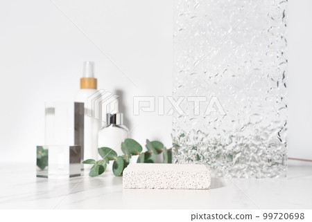 Cosmetics and beauty product presentation scene made with porous stone podium on white bathroom shelf. 99720698