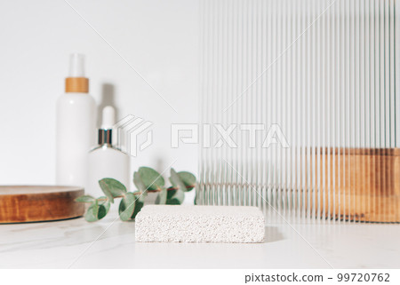 Spa and beauty product presentation scene made with porous stone podium near the cosmetic tubes and accessories on white bathroom shelf. Spa and beauty product presentation scene made with porous stone podium near the cosmetic tubes and accessories on white bathroom shelf. 99720762