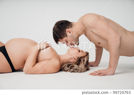 a passionate man and pregnan woman topless in black underwear on the floor 99720763
