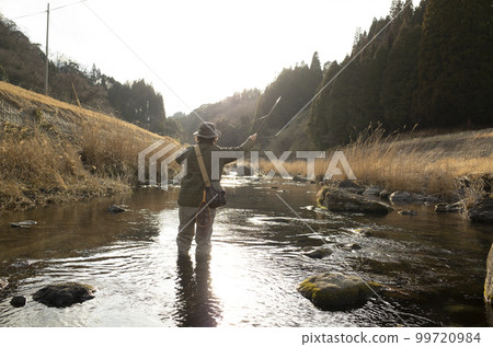 Man fly fishing in Satokawa in early spring 99720984