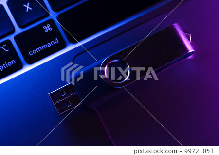 USB flash drive lying on a laptop keypad. 99721051