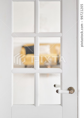 Old-style door, white - handle close up. The interior of a bright living room in a modern apartment. 99721205