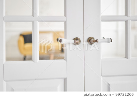 Old-style door, white - handle close up. The interior of a bright living room in a modern apartment. Old-style door, white - handle close up. The interior of a bright living room in a modern apartment. 99721206
