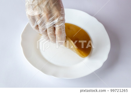 Young kombucha mushroom on a white plate on the table in a man's gloved hand. Tea fermentation. 99721265