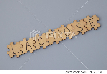 The word written on the wooden puzzles lettering is Lactose. On a blue background. The word written on the wooden puzzles lettering is Lactose. On a blue background. 99721306