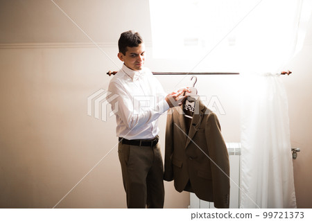 Grooms morning preparation. Handsome man getting dressed and preparing for the wedding 99721373