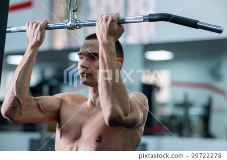 A man does a chest pulldown in the gym. 99722278