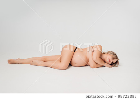 a naked pregnant against the background of a white cyclorama in a photo studio. a naked pregnant against the background of a white cyclorama in a photo studio. 99722885