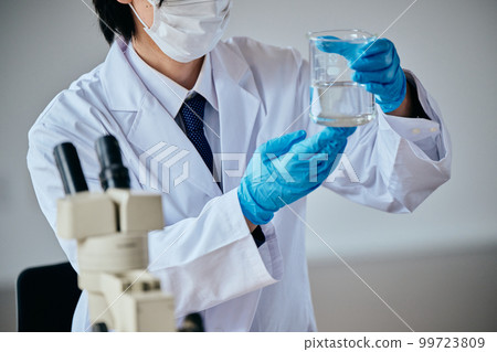 A young man in a white coat doing an experiment A young man in a white coat doing an experiment 99723809