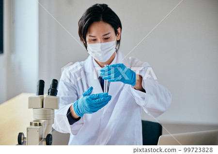 A young man in a white coat doing an experiment A young man in a white coat doing an experiment 99723828