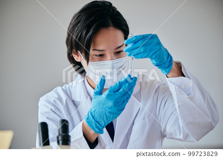 一個穿白大褂的年輕人在做實驗 99723829