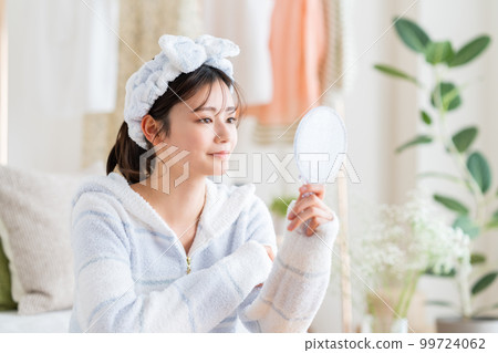 Young woman looking at a mirror Young woman looking at a mirror 99724062