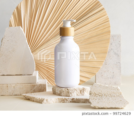 White One pump bottle on biege stones against dried palm leaf. Cosmetic Mockup White One pump bottle on biege stones against dried palm leaf. Cosmetic Mockup 99724629
