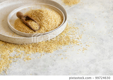 Pile of Dry uncooked bulgur wheat grain with a scoop on a plate close up, copy space. Healthy food Pile of Dry uncooked bulgur wheat grain with a scoop on a plate close up, copy space. Healthy food 99724630
