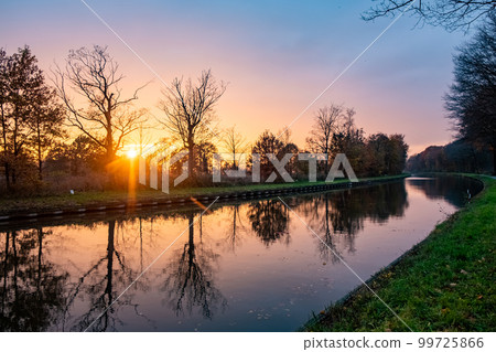 Beautiful sunset over a river with green bushes and color rich sky Beautiful sunset over a river with green bushes and color rich sky 99725866