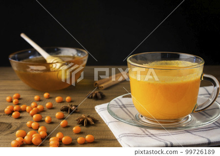 Tea of sea-buckthorn berries on wooden background Tea of sea-buckthorn berries on wooden background 99726189