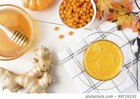 Tea with sea buckthorn juice with ginger and honey on a light wooden background. Tea with sea buckthorn juice with ginger and honey on a light wooden background. 99726192