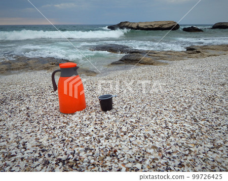 Orange thermos on the shore. 99726425
