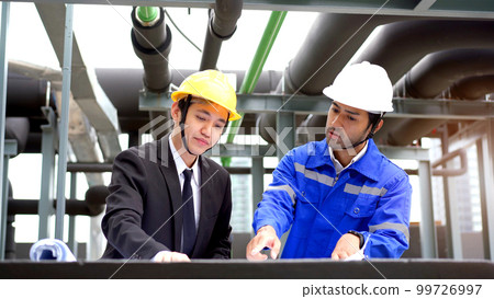 Professional Asian foreman and construction manager talking - discussing about building structure plant together. Businessman and construction engineer having a discussion. 99726997