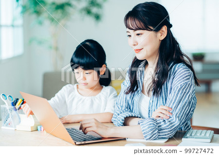 A daughter cuddling with a mother who works from home in the living room. A daughter cuddling with a mother who works from home in the living room. 99727472
