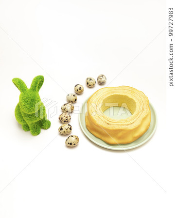 Green hare, rabbit with quail eggs and delicious baumkuchen, Sakotis ,sekacz pie on white background. Easter concept. Vertical plane Green hare, rabbit with quail eggs and delicious baumkuchen, Sakotis ,sekacz pie on white background. Easter concept. Vertical plane 99727983