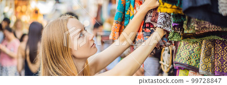 Woman traveler choose souvenirs in the market at Ubud in Bali, Indonesia BANNER, LONG FORMAT Woman traveler choose souvenirs in the market at Ubud in Bali, Indonesia BANNER, LONG FORMAT 99728847
