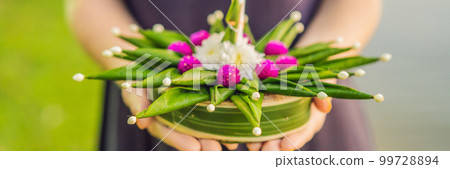 BANNER, LONG FORMAT A female tourist holds the Loy Krathong in her hands and is about to launch it into the water. Loy Krathong festival, People buy flowers and candle to light and float on water to 99728894