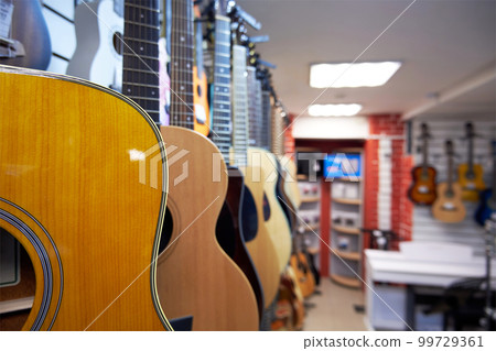 Different acoustic six-string guitars in a music store 99729361