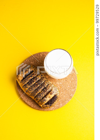 Breakfast bread and a cup of milk on yellow and blue background 99729529