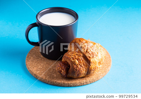 Breakfast bread and a cup of milk on yellow and blue background 99729534