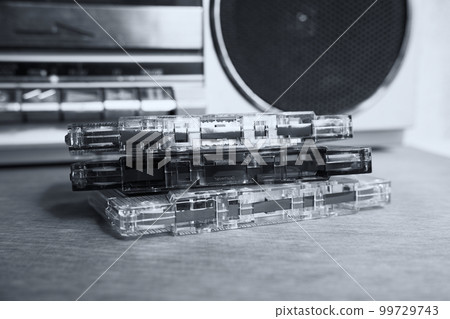 Audio cassettes without boxes lie on the table against the background of a tape recorder 99729743